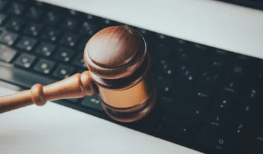 A wooden gavel resting on the keyboard of a laptop