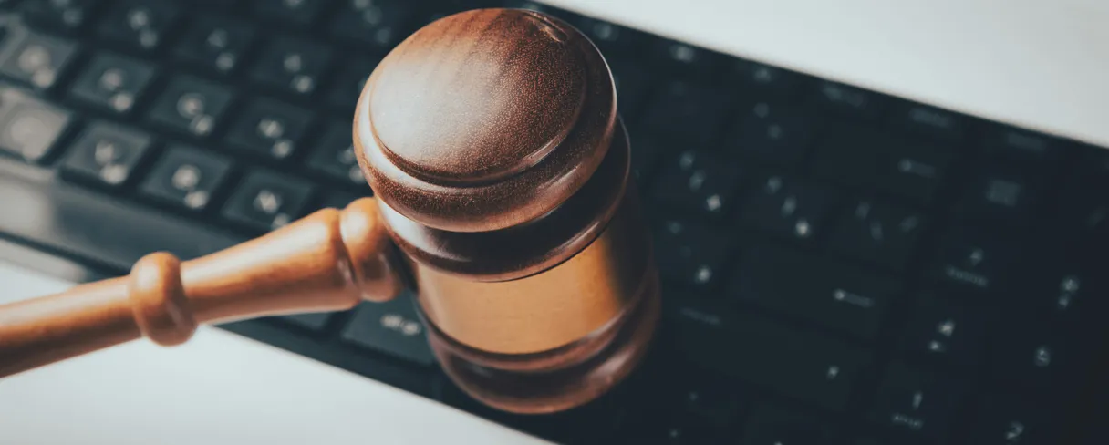 A wooden gavel resting on the keyboard of a laptop