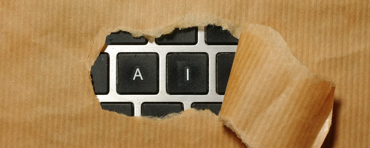 Torn brown packing paper pulled back to reveal keyboard keys spelling AI
