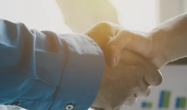 Two people shaking hands in front of a business chart